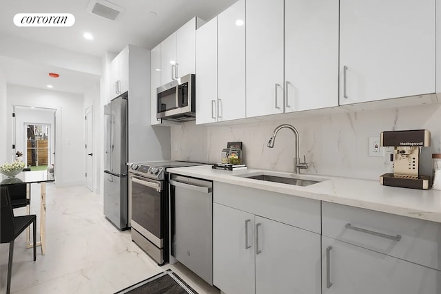 kitchen featuring white cabinetry, sink, decorative backsplash, and appliances with stainless steel finishes