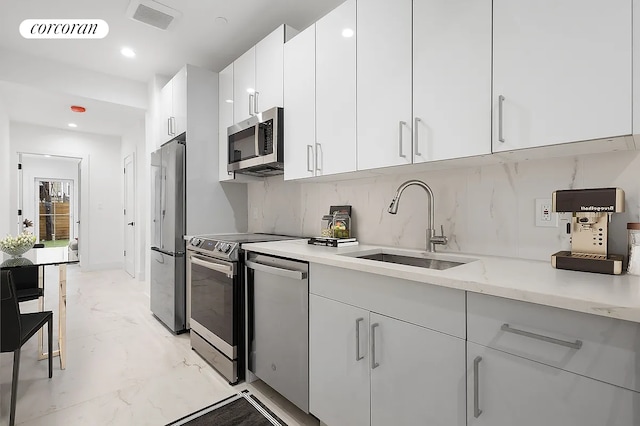 kitchen featuring visible vents, a sink, appliances with stainless steel finishes, white cabinetry, and marble finish floor