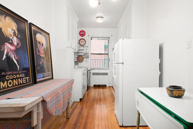 kitchen with white cabinetry, radiator heating unit, white refrigerator, and light wood-type flooring