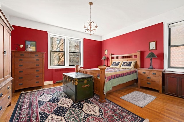 bedroom with radiator, light hardwood / wood-style flooring, and a notable chandelier