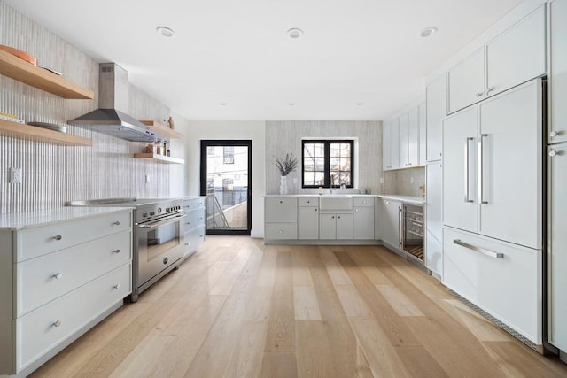 kitchen featuring wine cooler, exhaust hood, light hardwood / wood-style floors, white cabinetry, and high end appliances