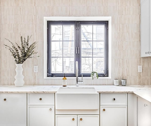 kitchen featuring a healthy amount of sunlight, white cabinets, light stone counters, and sink