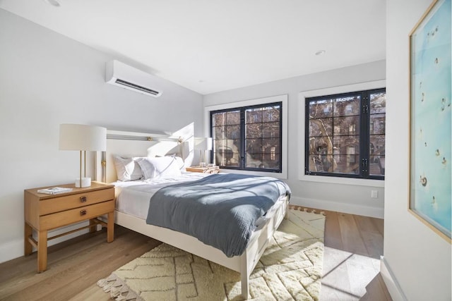 bedroom with light hardwood / wood-style floors and a wall mounted air conditioner