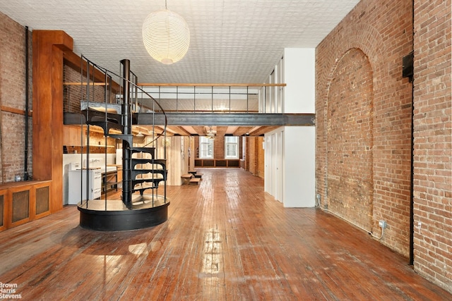 interior space with a high ceiling, brick wall, and hardwood / wood-style floors