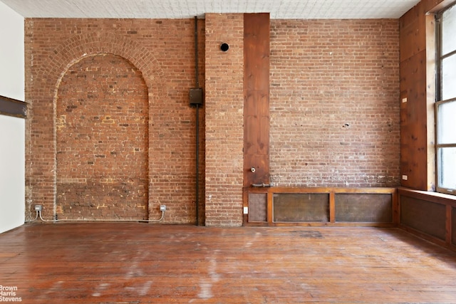 spare room featuring brick wall and hardwood / wood-style floors