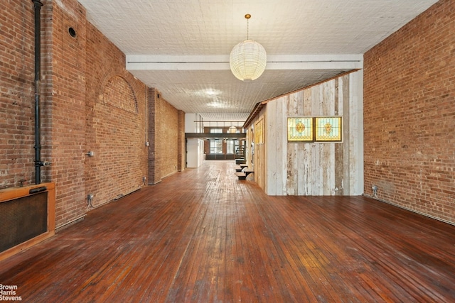 unfurnished room featuring wood-type flooring and brick wall