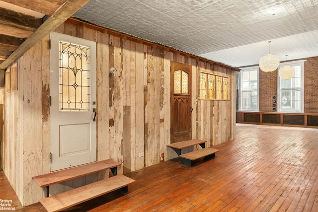 mudroom with hardwood / wood-style floors and wooden walls