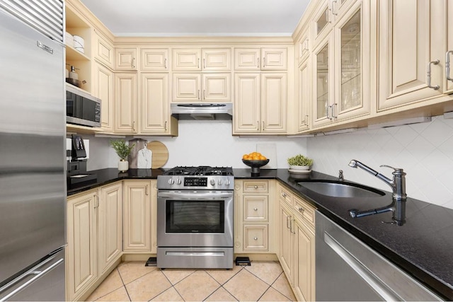 kitchen with light tile patterned flooring, appliances with stainless steel finishes, cream cabinets, and sink