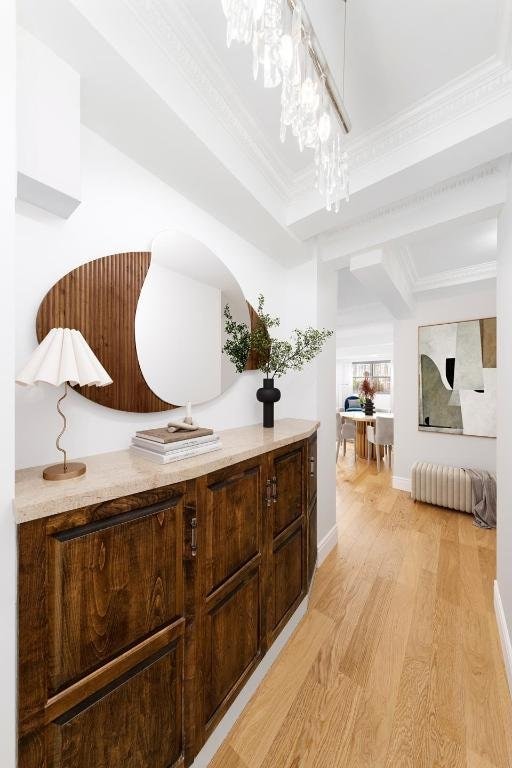 interior space with light wood-type flooring, ornamental molding, and a notable chandelier