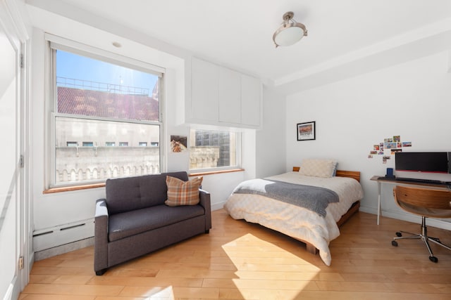 bedroom featuring a baseboard heating unit and light hardwood / wood-style flooring