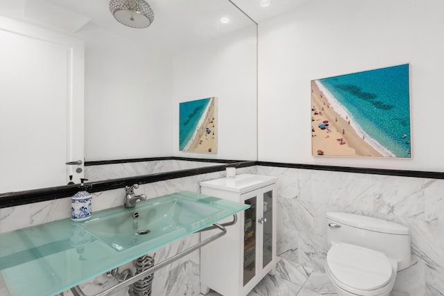 bathroom featuring toilet, tile walls, and vanity