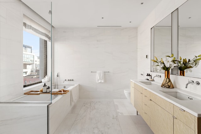 bathroom featuring tiled bath, tile walls, toilet, and vanity