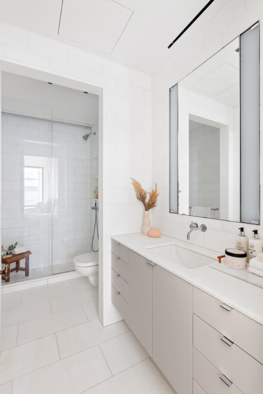 bathroom featuring toilet, tile patterned flooring, tiled shower, and vanity