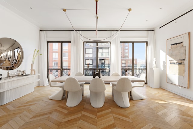 dining area featuring light parquet flooring, ornamental molding, and a healthy amount of sunlight