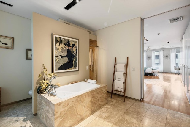 bathroom featuring toilet, tile patterned flooring, a relaxing tiled tub, and ceiling fan