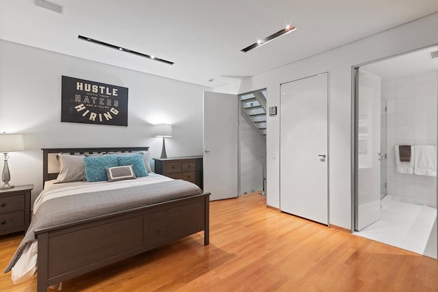 bedroom featuring connected bathroom and light hardwood / wood-style floors