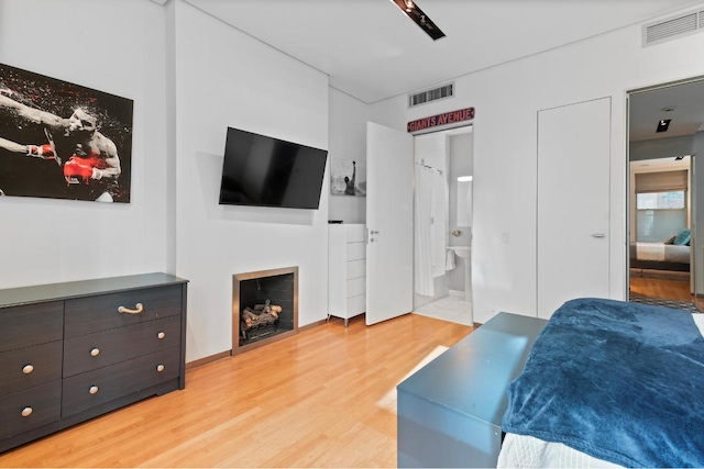 bedroom with ceiling fan, connected bathroom, and light hardwood / wood-style flooring