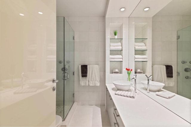 bathroom featuring a shower with shower door, tile walls, and vanity