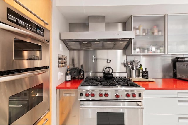 kitchen with white cabinets, appliances with stainless steel finishes, and wall chimney exhaust hood