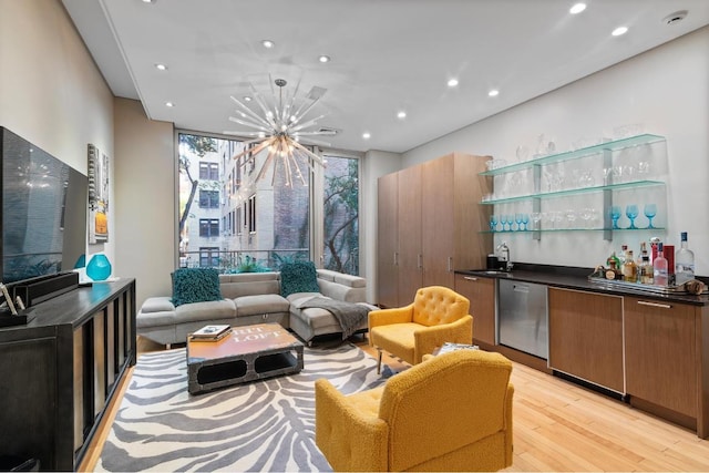 interior space featuring floor to ceiling windows, a notable chandelier, stainless steel dishwasher, light hardwood / wood-style flooring, and sink