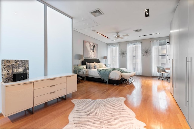 bedroom with ceiling fan, light hardwood / wood-style floors, and multiple windows