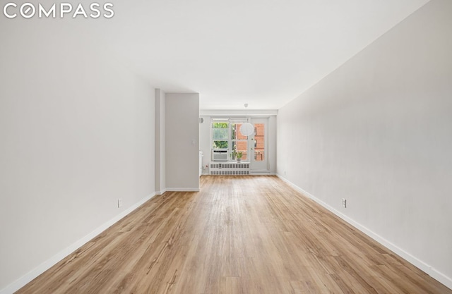 unfurnished room featuring radiator heating unit and light hardwood / wood-style flooring