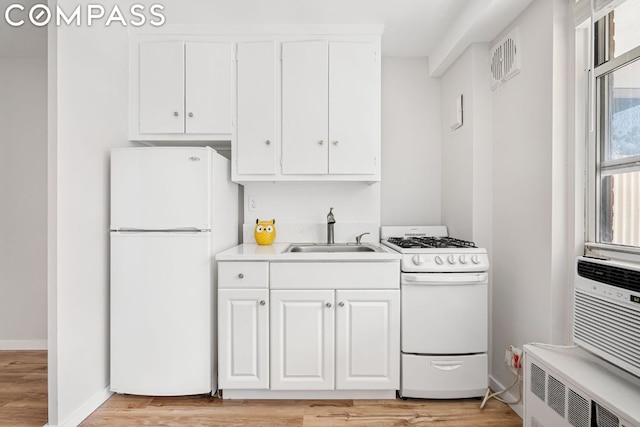 kitchen with white appliances, white cabinets, radiator, sink, and light hardwood / wood-style flooring