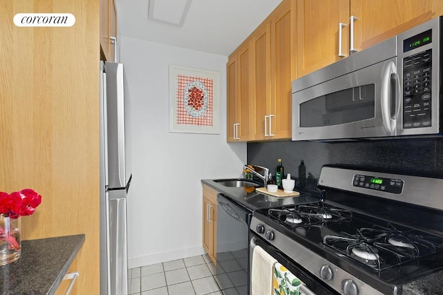 kitchen with sink, light tile patterned floors, stainless steel appliances, and dark stone counters