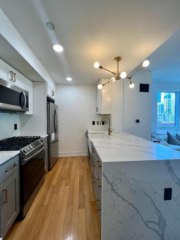 kitchen with white cabinets, light hardwood / wood-style flooring, stainless steel appliances, sink, and gray cabinetry