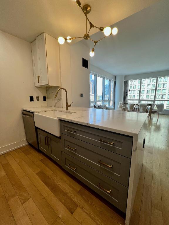 kitchen featuring hardwood / wood-style flooring, kitchen peninsula, stainless steel dishwasher, white cabinets, and sink