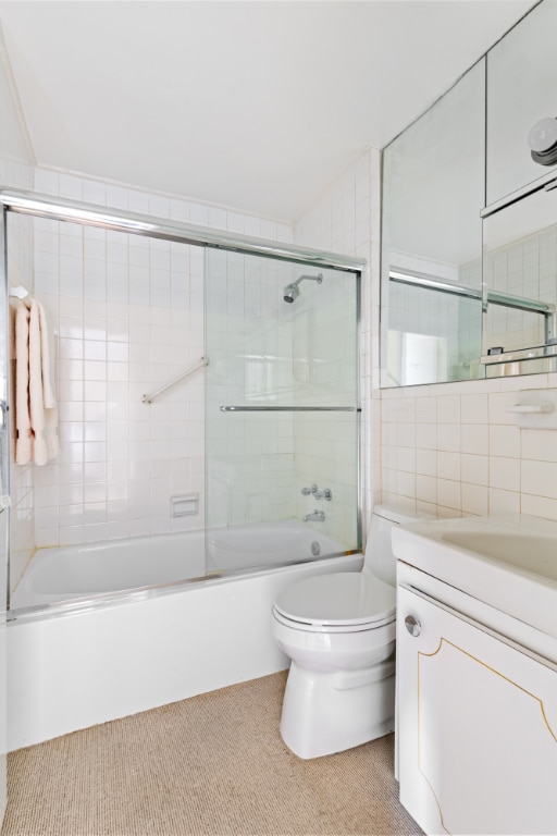 full bathroom with tile walls, enclosed tub / shower combo, vanity, and toilet