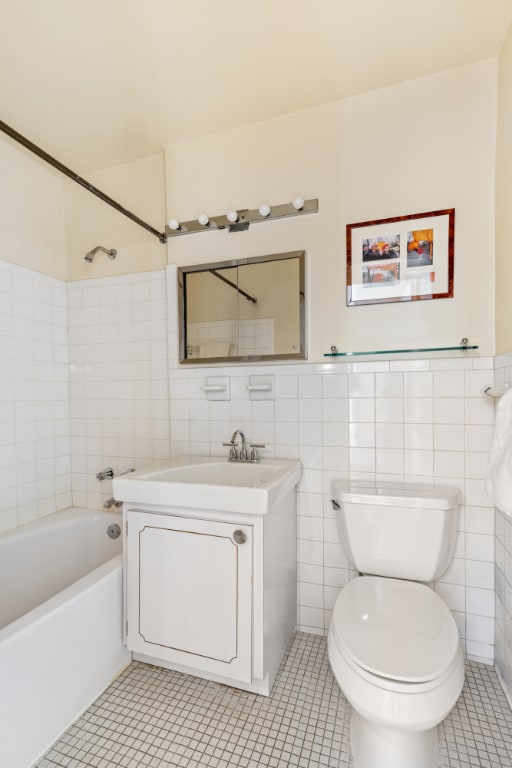 full bathroom with toilet, vanity, tile walls, and tile patterned floors