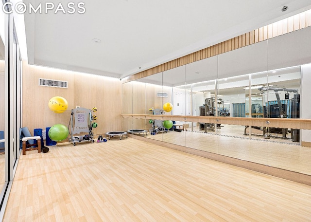 gym featuring ceiling fan, wood-type flooring, and wooden walls