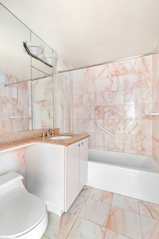 full bathroom featuring toilet, vanity, tile walls, and bathtub / shower combination