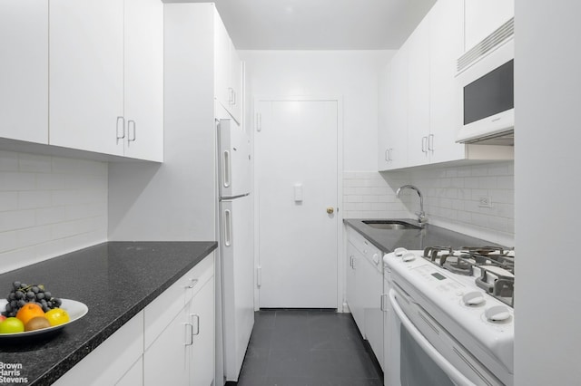 kitchen featuring dark tile patterned flooring, white appliances, white cabinets, decorative backsplash, and sink