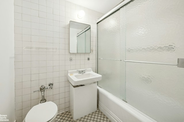 full bathroom featuring toilet, tile walls, enclosed tub / shower combo, and sink