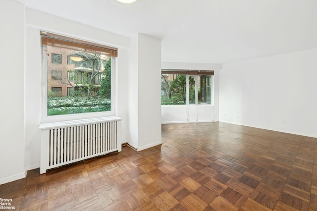 empty room with dark parquet flooring and radiator