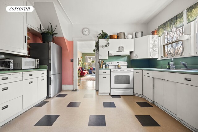 kitchen featuring a healthy amount of sunlight, sink, white electric range, and white cabinets