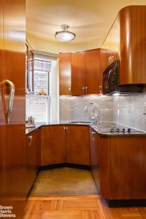 kitchen featuring decorative backsplash, light parquet flooring, black appliances, and sink