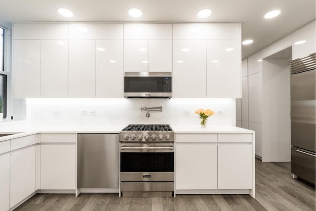 kitchen featuring tasteful backsplash, sink, white cabinetry, light wood-type flooring, and stainless steel appliances