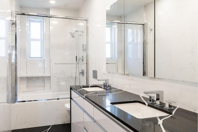 full bathroom with combined bath / shower with glass door, vanity, and toilet