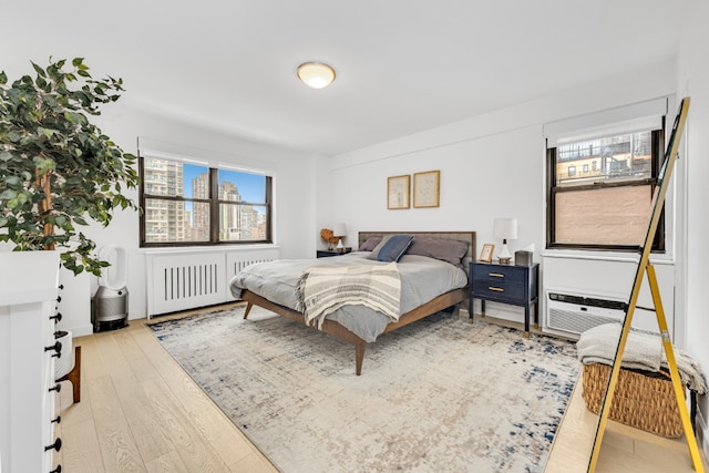 bedroom featuring radiator heating unit and light hardwood / wood-style floors