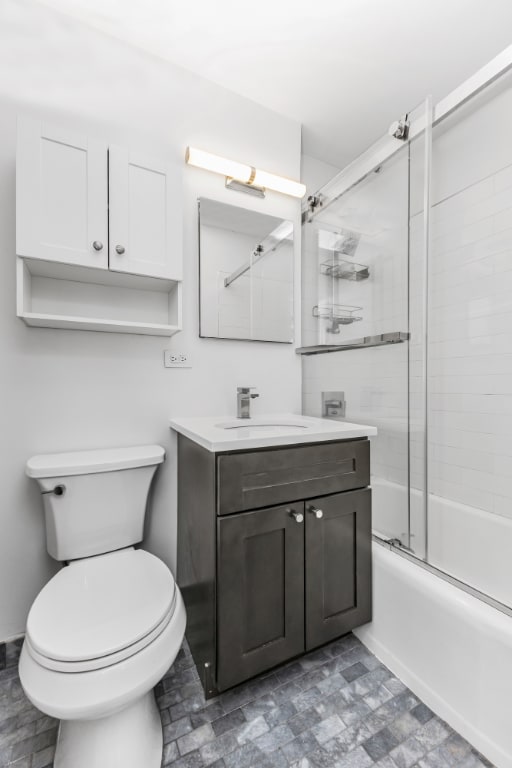 full bathroom featuring toilet, vanity, and shower / bath combination with glass door