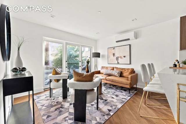 living room with a wall mounted air conditioner and hardwood / wood-style flooring