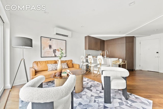 living room featuring a wall mounted air conditioner and light hardwood / wood-style floors