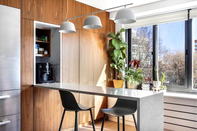 bar featuring decorative light fixtures and built in refrigerator