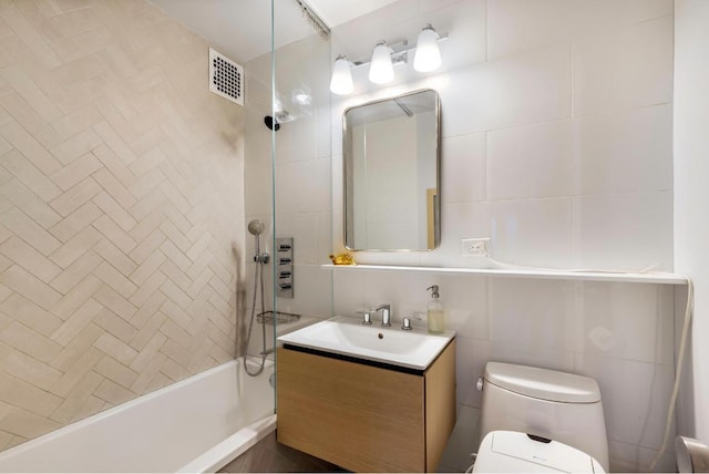 full bathroom featuring toilet, tasteful backsplash, tile walls, vanity, and tiled shower / bath combo