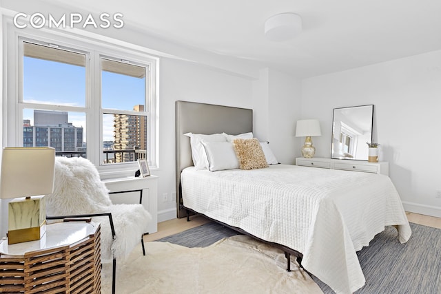 bedroom with a view of city, baseboards, and wood finished floors