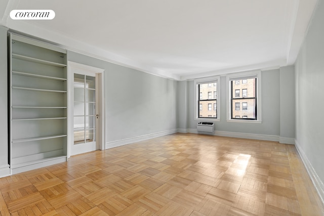 spare room featuring an AC wall unit, visible vents, and baseboards