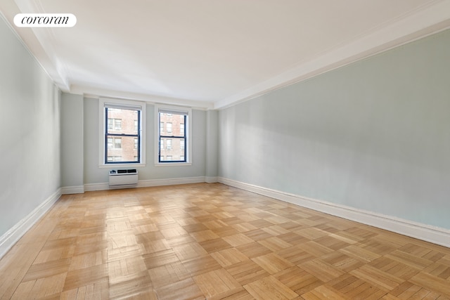 spare room featuring crown molding, an AC wall unit, and light parquet flooring